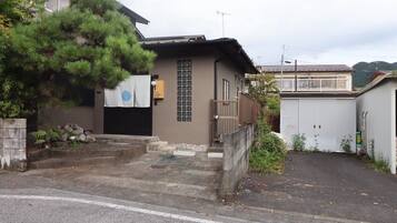 A residential building with a small front yard, a gate, and a driveway leading to a garage.