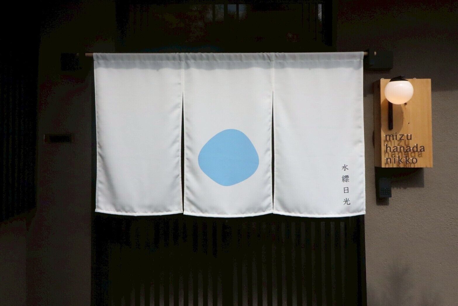 A white curtain with a blue circle and Japanese text hanging on a wall.