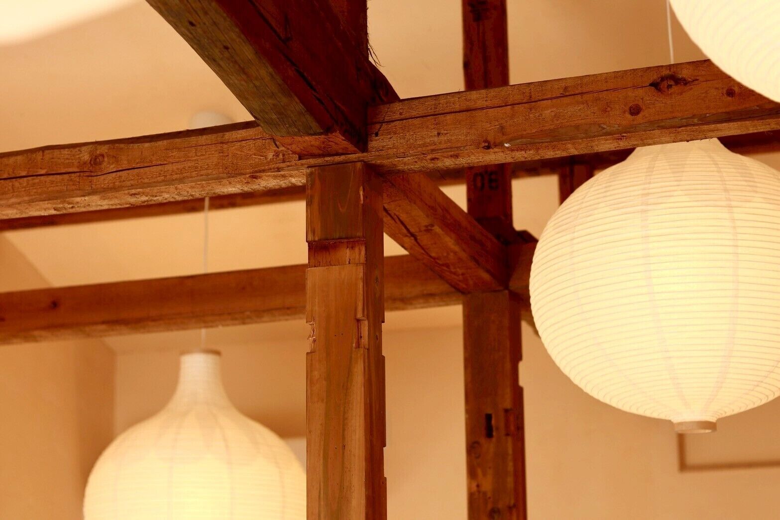 Une structure de plafond en bois avec des poutres apparentes et des lanternes en papier suspendues.