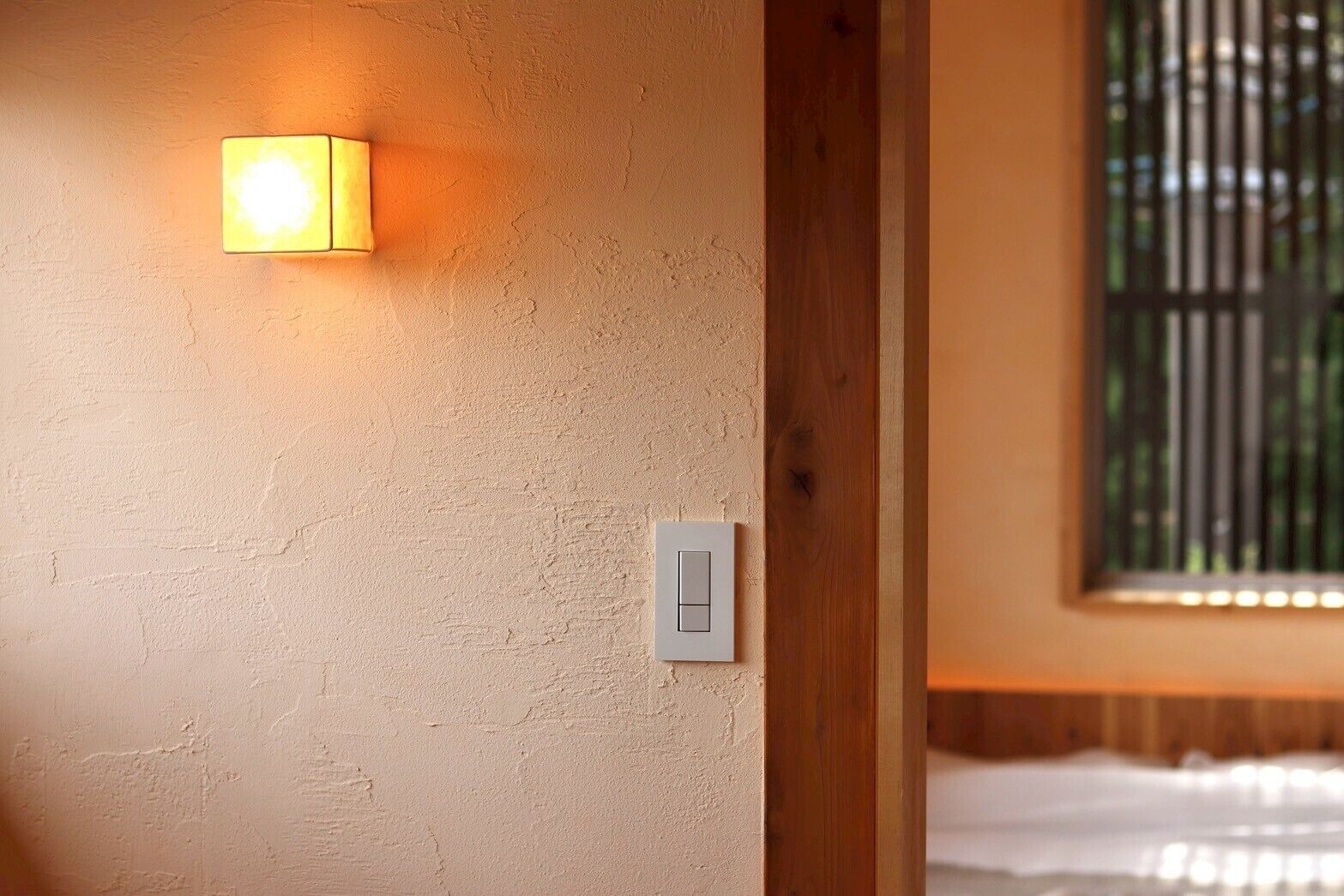 Pared texturizada con un accesorio de luz empotrado y un interruptor de luz estándar.