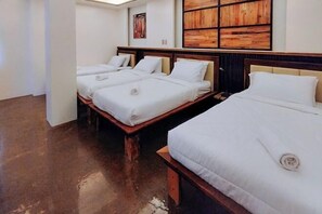 A hotel room with three beds, wooden headboards, and a large wooden panel artwork on the wall. - Estancia Roadside Inn by RedDoorz (Estancia)