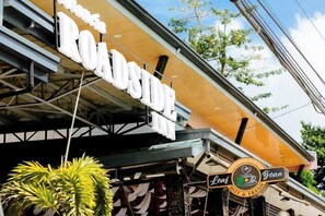 A building with a sign that reads 'ROADSIDE' and another sign for 'Coast Brew'. - Estancia Roadside Inn by RedDoorz (Estancia)