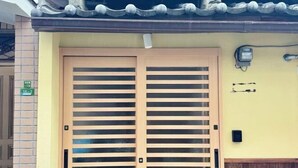 A wooden door with horizontal slats, a tiled roof, and a wall-mounted electrical box. - Kitagatsukyo｜Direct train to Osaka Castle, Shinsaibashi, and Tsutenkaku (Osaka)