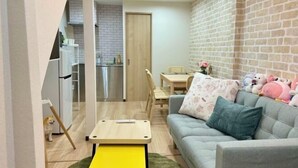 A cozy living room with a sofa, a small table, and a brick wall. - Kitagatsukyo｜Direct train to Osaka Castle, Shinsaibashi, and Tsutenkaku (Osaka)