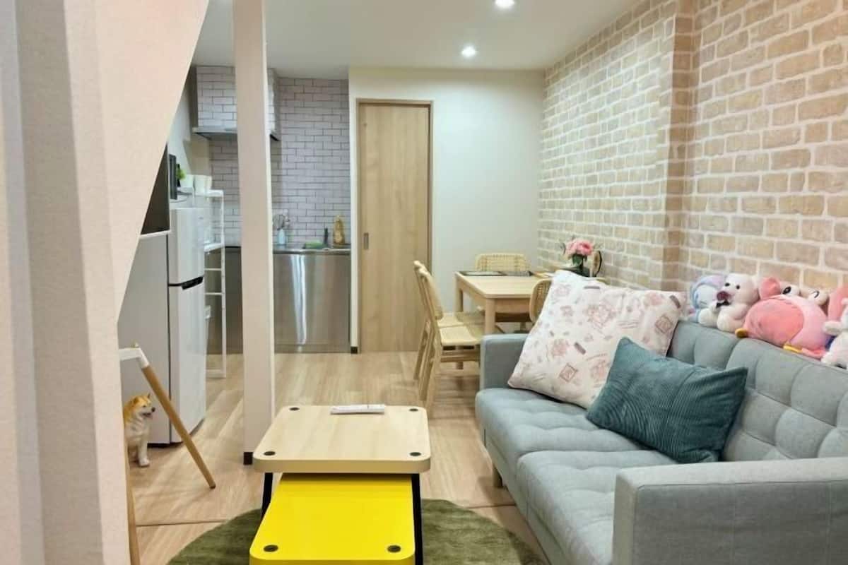 A cozy living room with a sofa, a small table, and a brick wall.