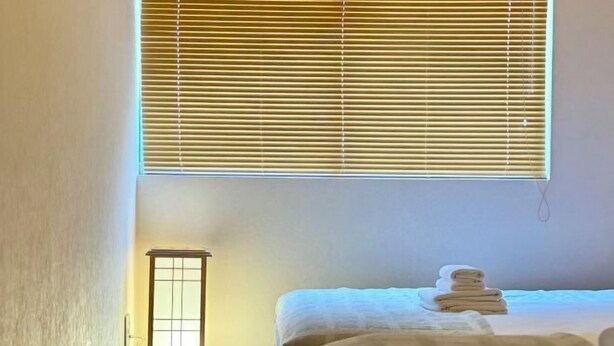 A hotel room with a bed, a bedside table, a lamp, and a window with blinds. - Kitagatsukyo｜Direct train to Osaka Castle, Shinsaibashi, and Tsutenkaku (Osaka)
