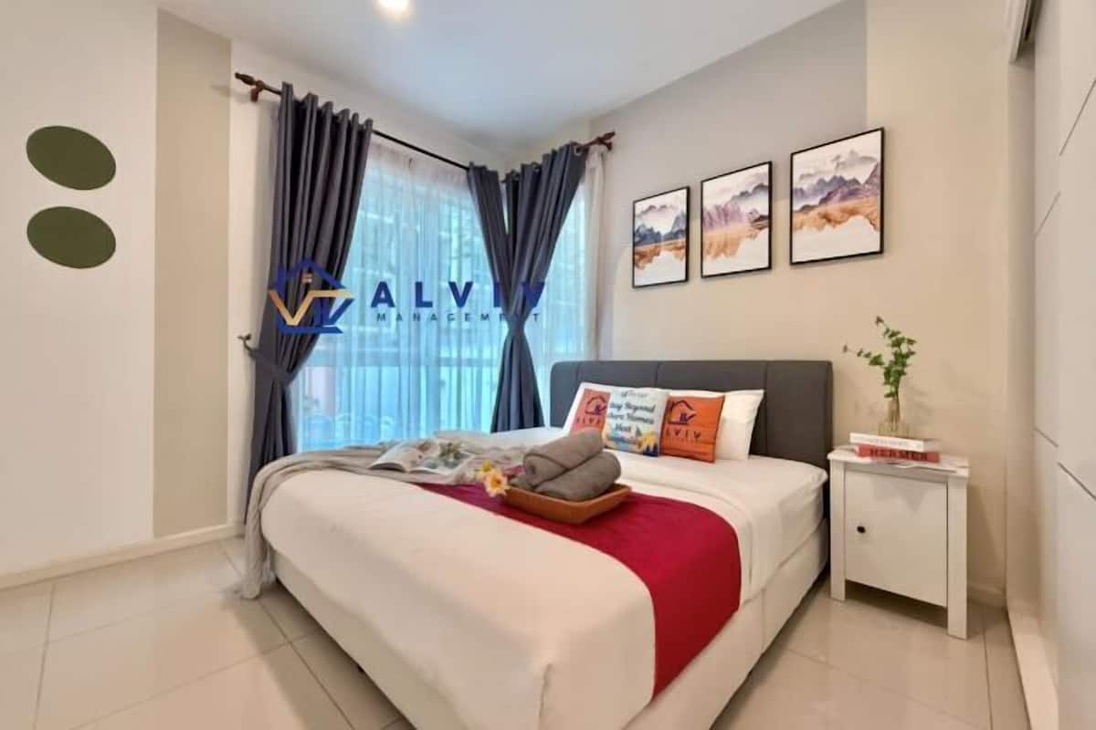A modern bedroom with a bed, curtains, a nightstand, and framed artwork on the wall.