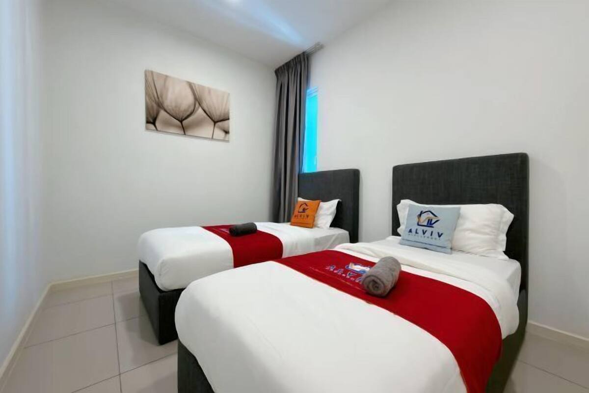 A hotel room with two beds, each with a pillow and a blanket.