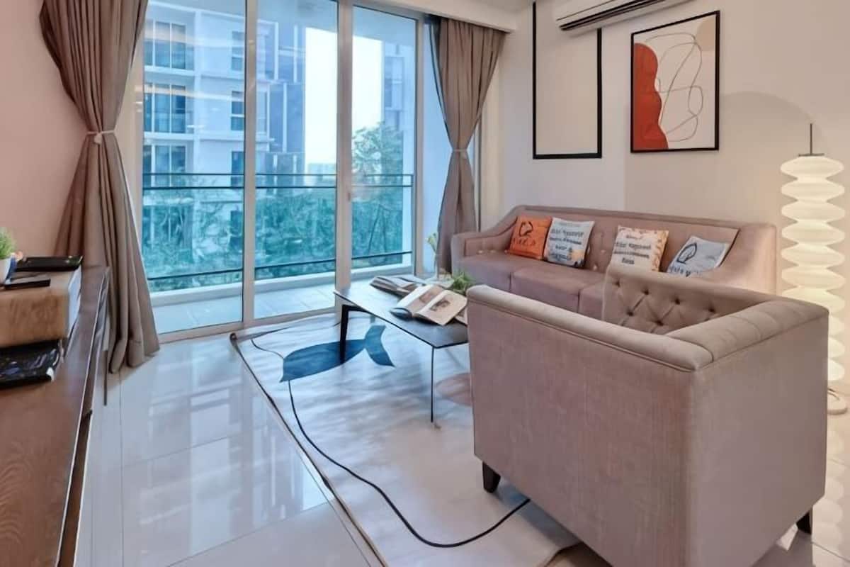 A modern living room with a sofa, a coffee table, and a large window with curtains.