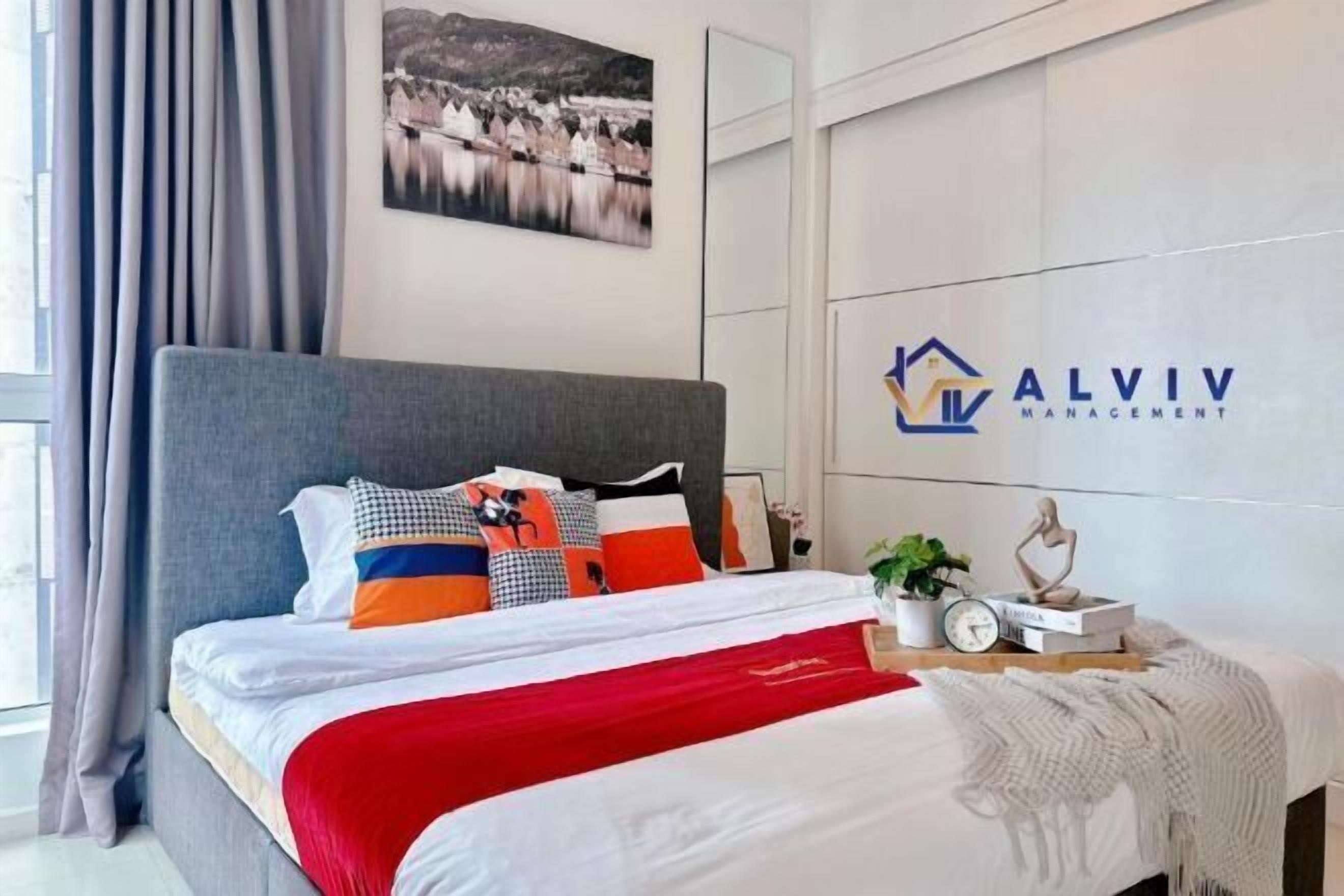 Una camera d'albergo moderna con un grande letto, un quadro raffigurante un panorama cittadino e un logo appeso al muro.