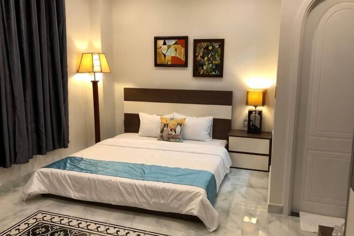 A hotel room with a bed, nightstands, lamps, and artwork on the walls.