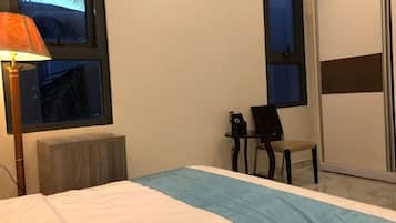 Une chambre d’hôtel avec un lit, un bureau, une chaise et une fenêtre donnant sur un paysage agréable.