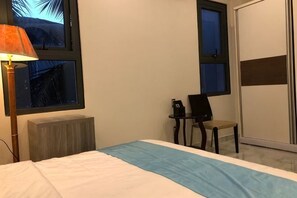 Ein Hotelzimmer mit Bett, Schreibtisch, Stuhl und einem Fenster mit Blick.