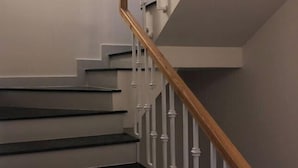 A staircase with white balusters and a wooden handrail. - Longs Beach House Hồ Tràm - Beachfront Sea View Villa (Xuyen Moc District)