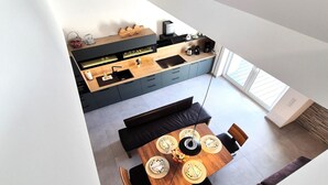 A modern kitchen with a central island, a dining area with a wooden table, and a view of the living space. - Duplex in Winterberg near Market Square (Winterberg)