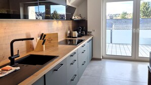 A modern kitchen with a wooden countertop, black sink, and grey cabinets. - Duplex in Winterberg near Market Square (Winterberg)