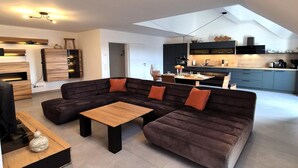 A modern living space with a sectional sofa, a wooden coffee table, and a dining area with a kitchen in the background. - Duplex in Winterberg near Market Square (Winterberg)