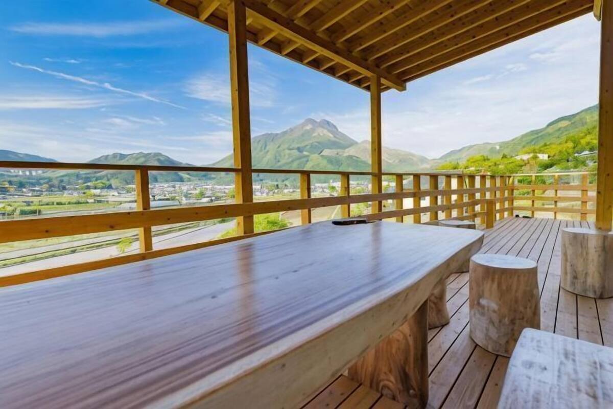 A wooden deck with a table and benches, overlooking a mountainous landscape.