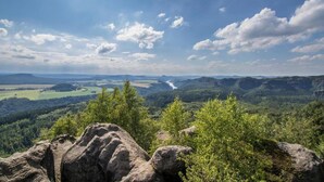 Un paysage montagneux avec une rivière, une forêt dense et des affleurements rocheux.