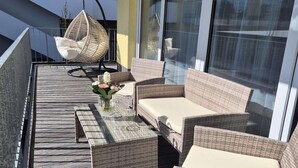 A balcony with wicker furniture, including a sofa and chairs, and a hanging chair. - Winterberg comfort for 4 guests (Winterberg)