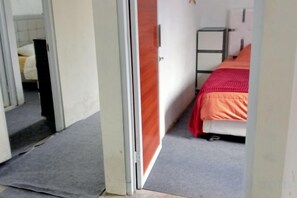 Una habitación con una cama, un armario y una puerta que da a otra estancia.