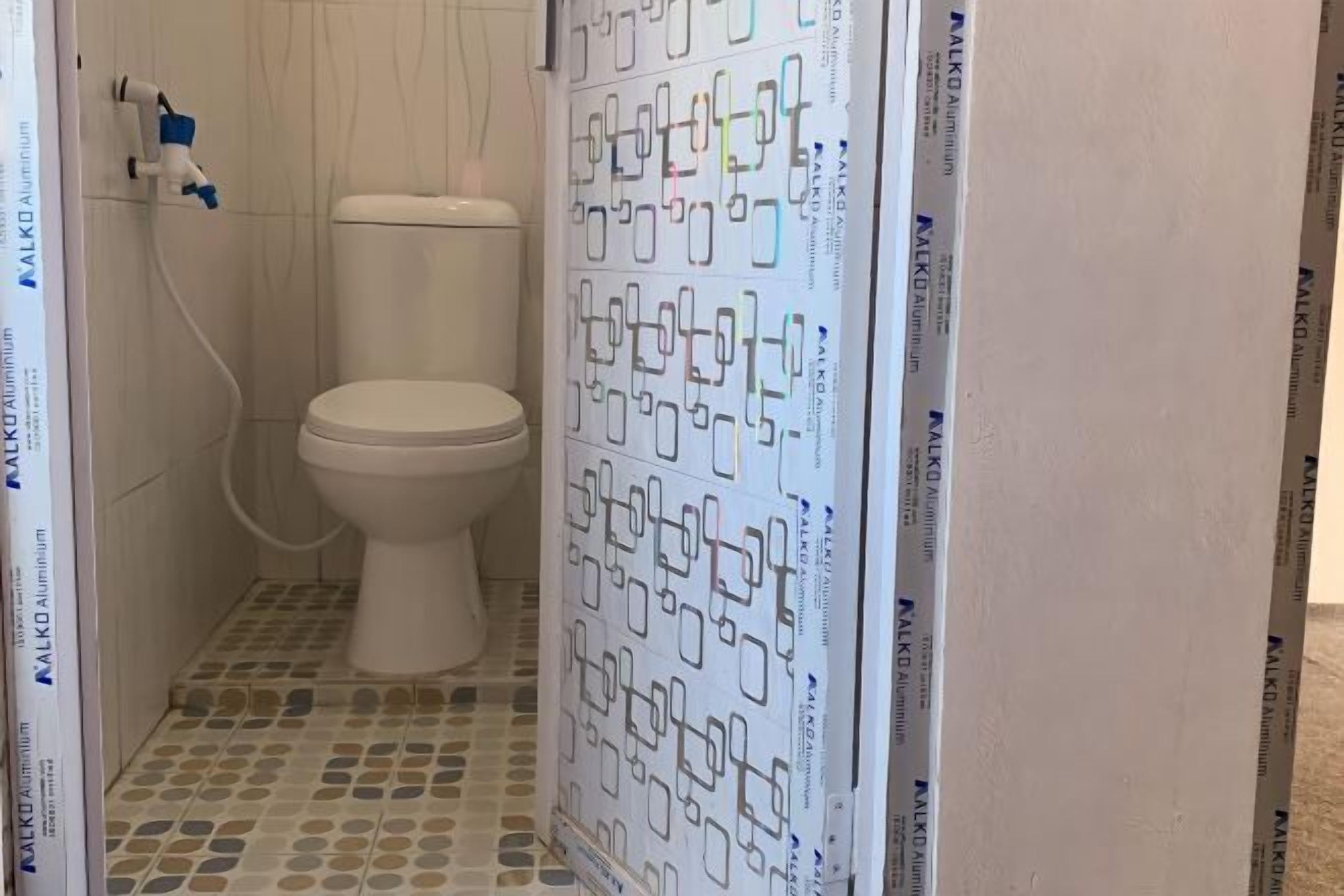 A bathroom with a toilet, a shower area, and a tiled floor.