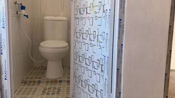 A bathroom with a toilet, a shower area, and a tiled floor.