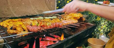 A grill with various meats and vegetables being cooked.