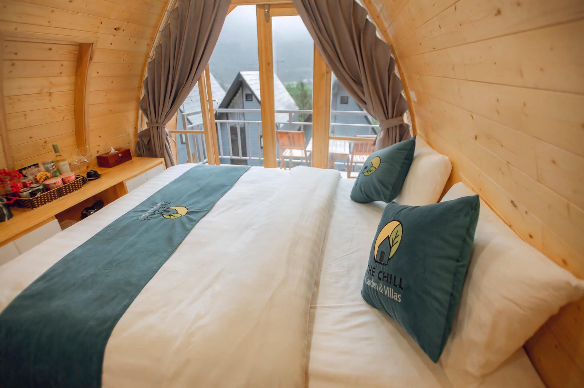 A cozy wooden cabin bedroom with a bed, pillows, and a small table with items.