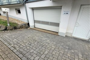 A garage with a closed white door, a sign indicating no parking, and a paved driveway.