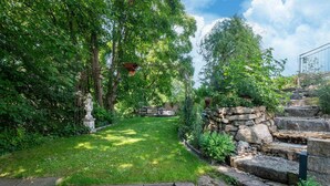 A garden with a stone wall, a statue, and a wooden bench.