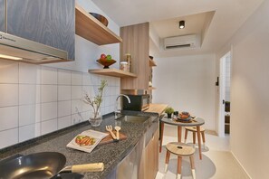 A modern kitchen with a granite countertop, built-in appliances, wooden shelves, and a dining area with stools. - lyf Farrer Park Singapore (Singapore)