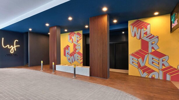 Un vestíbulo moderno con un letrero de neón, arte mural geométrico y un mostrador de recepción.