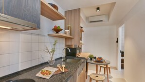 Una cocina moderna con encimera de granito, electrodomésticos integrados, estanterías de madera y una zona de comedor con taburetes.