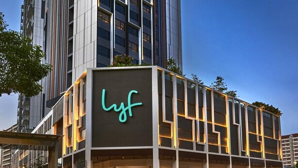 Ein modernes Hotelgebäude mit einem gut sichtbaren 'lyf'-Schild, mehreren Etagen und einer Glasfassade.