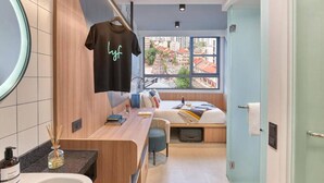 A modern bathroom with a wooden vanity, a hanging towel, and a bed with a view of buildings. - lyf Farrer Park Singapore (Singapore)