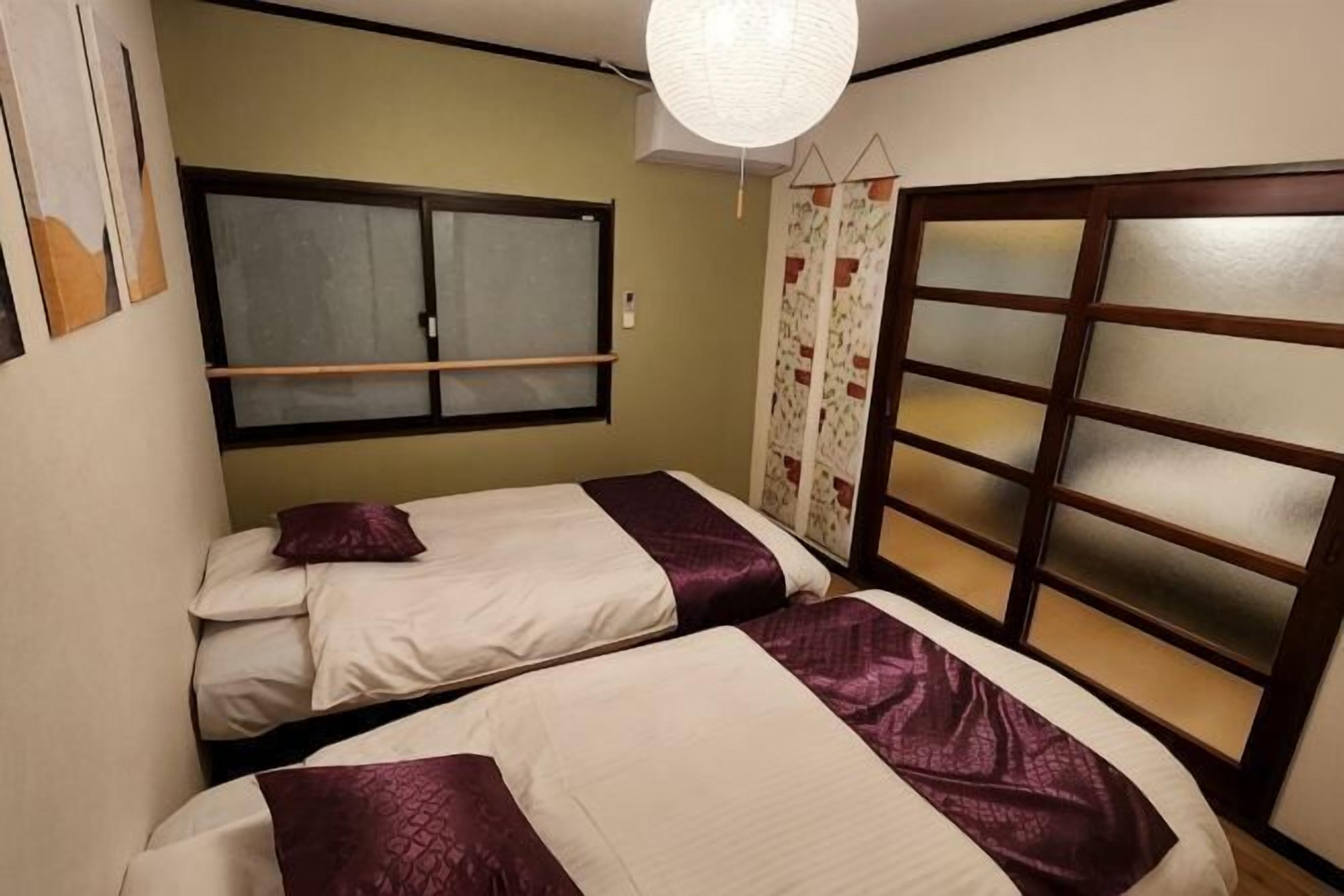 A room with two beds, a window, and a sliding door.