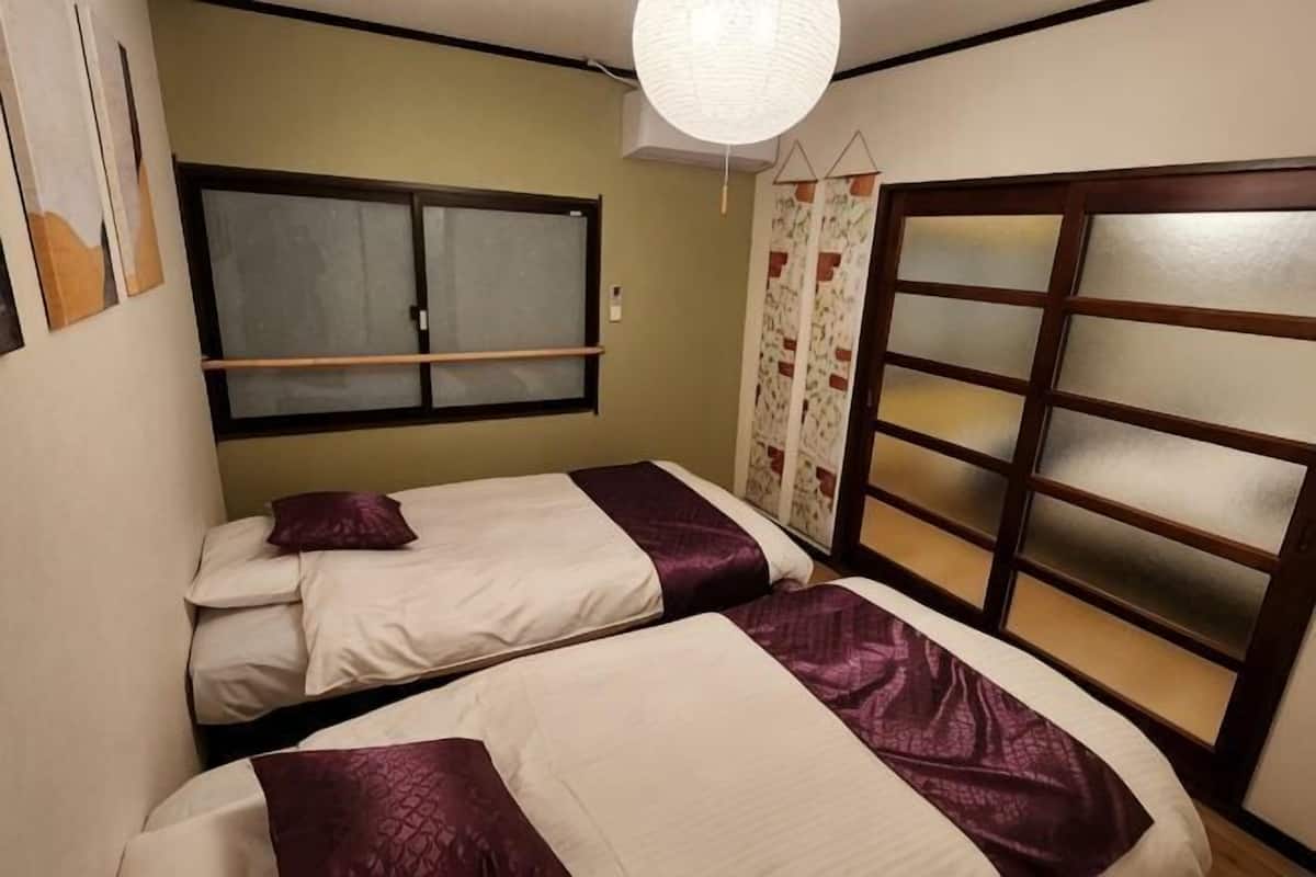 Una habitación con dos camas, una ventana y una puerta corrediza.