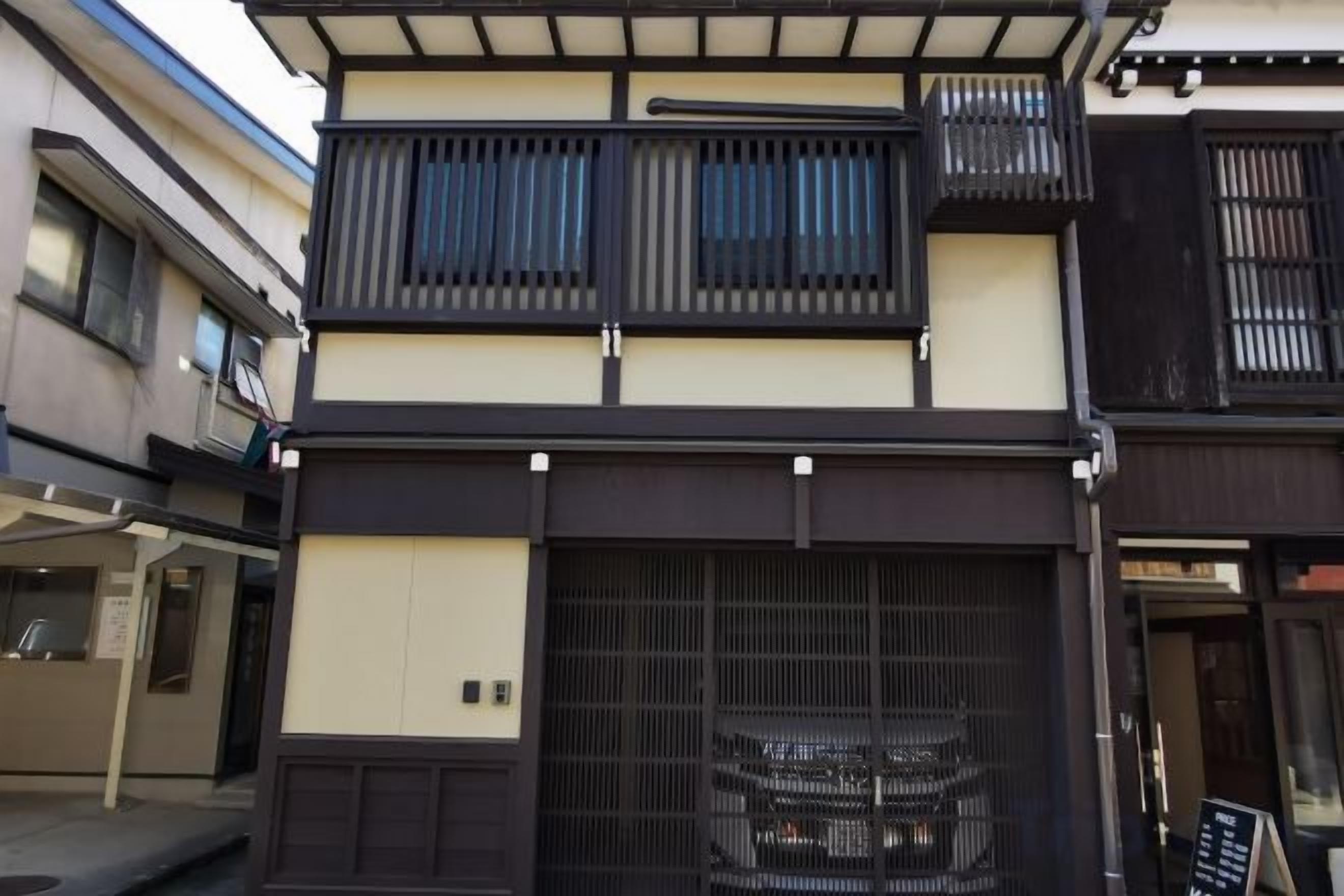 A multi-story building with a traditional Japanese architectural style, featuring a sliding door and a balcony.