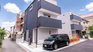 A modern multi-story residential building with a black car parked in front. - New open ! TabiTaimu・Momodani MOMO｜Near Tennoji Park & Shinsekai｜Direct Train to Osaka Castle (Osaka)