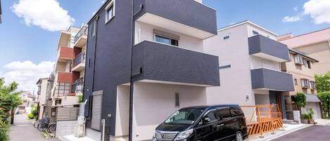 Un edificio residencial moderno de dos pisos con un automóvil negro estacionado frente a él.