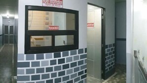 A hotel corridor with a brick-patterned wall, a window with a sign above it, and a door to the right.