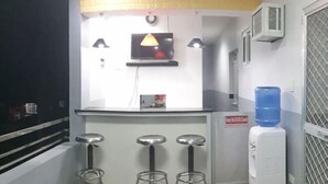 A bar area with a counter, three stools, a television, and a water dispenser.