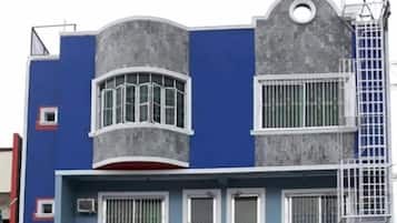 A building with a blue facade, a curved balcony, and a window with a white frame.