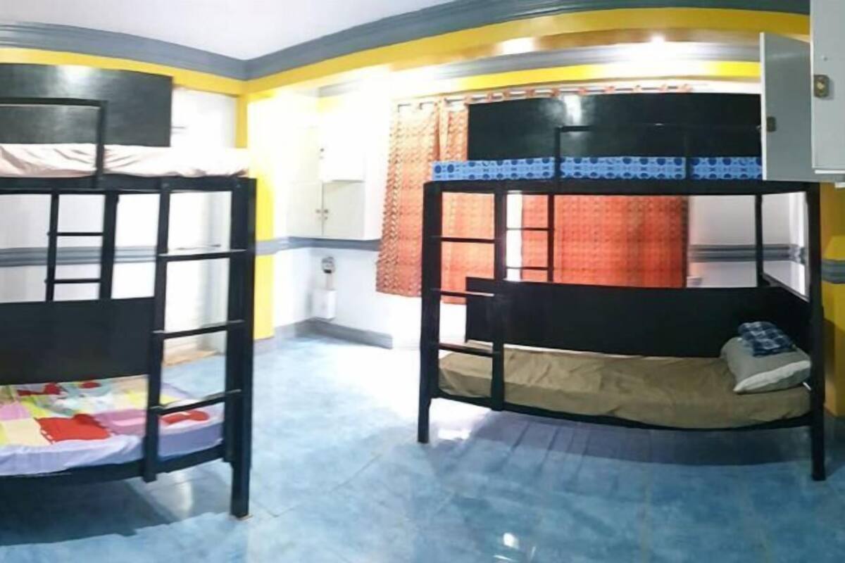 A room with bunk beds, a small desk, and a window with curtains.