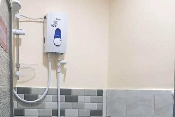 Une salle de bain équipée d’une douche murale, d’un carrelage au sol et d’un sèche-mains.