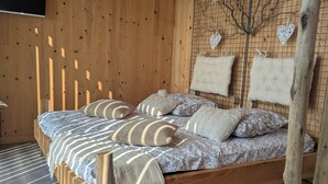 A wooden room with a bed, a TV, and a wall with heart-shaped decorations. - Tiny house-style chalet with private spa on the Alsace border (Zilling)