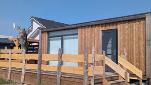 A wooden cabin with a large window and a door, surrounded by a wooden fence. - Tiny house-style chalet with private spa on the Alsace border (Zilling)