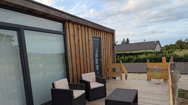 A modern outdoor patio with wicker furniture and a wooden deck. - Tiny house-style chalet with private spa on the Alsace border (Zilling)