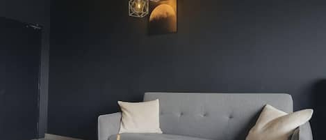 A modern living room with a grey sofa, a round coffee table, and a pendant light fixture.